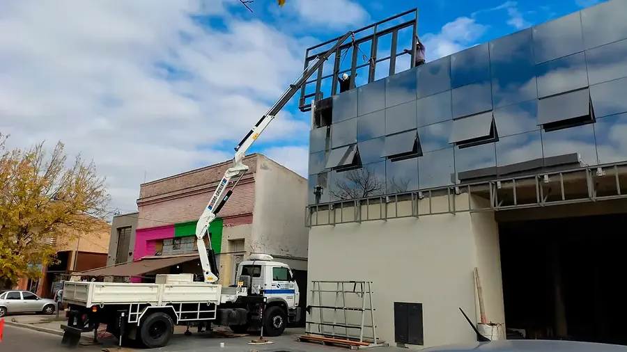 Hidrogrúa de Metalúrgica Salafia montando una estructura sobre una fachada urbana